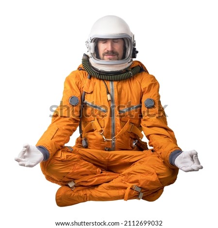Calm astronaut wearing orange space suit and space helmet sitting in a lotus yoga pose meditating isolated on a white background. Meditation mental concept