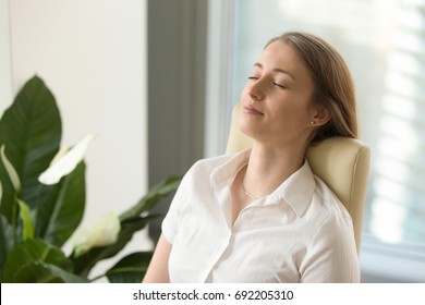 Calm attractive woman feeling relaxed in office home, peaceful mindful businesswoman leaning back on chair with eyes closed, meditating at work, taking deep breath to relax, no stress at workplace