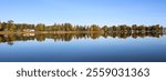 Calm autumn day, colorful trees reflecting in Lake Vanern, Sweden.