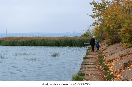 Calm autumn landscape with a family on a walk, mother and child walking by the pond, nature in autumn, morning fog, falling leaves, casual clothes, yellow foliage, space for text, reeds,old embankment - Shutterstock ID 2365381623