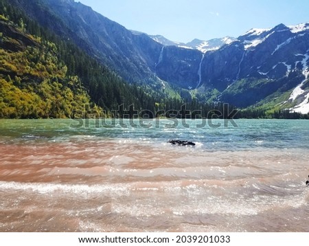 calm beach with lush mountain range and waterfall