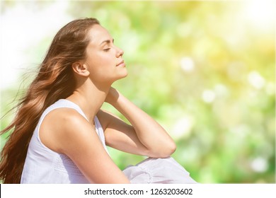 Calm Beautiful Smiling Young Woman With Ponytail Enjoying Fresh Air Outdoor, Relaxing With Eyes Closed, Feeling Alive, Breathing, Dreaming. Copy Space, Green Park Nature Background. Side View Portrait