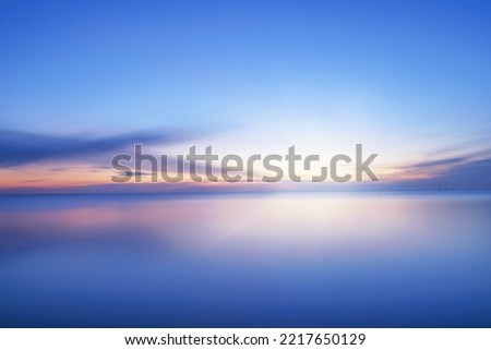 Calm blue colored sea and clear sky at sunset. Extreme long exposure, horizontal view