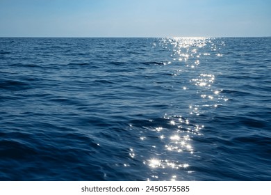 Calm blue sea shimmers with reflections of the sun creating a path of light on the waters surface - Powered by Shutterstock