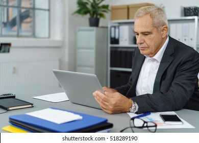 Calm Business Owner Checking His Laptop Computer In Small Office With Window. Includes Copy Space.