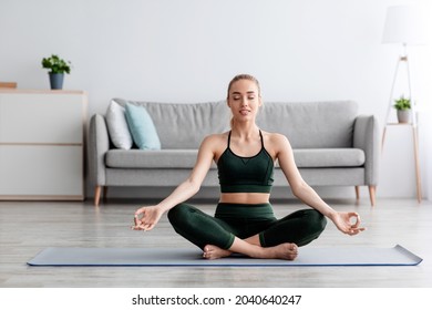 Calm caucasian pretty young blonde lady with closed eyes practicing yoga, breath, exercising at home alone, enjoy peace and freedom, empty space. Rest, relax and sports in minimal living room interior - Powered by Shutterstock