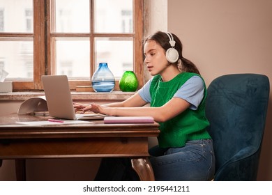 Calm Caucasian Teen Child Wearing Headphones Typing At The Laptop Computer