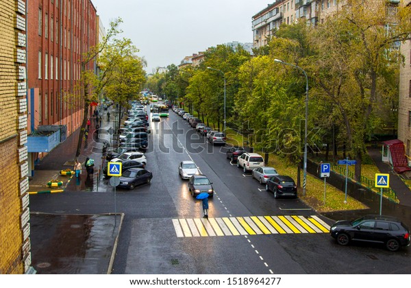 calm\
city street with cars and pedestrians in the\
rain