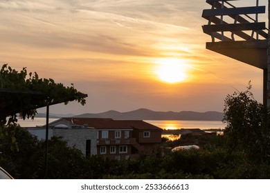 Calm coastal landscape with tranquil sea and a beautiful sunset, distant islands, and residential houses overlooking the water. Concept of peaceful scenery, island living, and natural beauty at sunset - Powered by Shutterstock