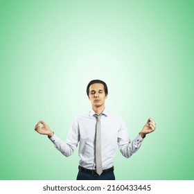 Calm Down Concept With Man In White Shirt In A Zen Pose Isolated On Light Green Wall Background With Empty Place For Your Text Or Logo, Mock Up