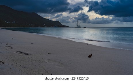 Calm evening seascape. Footprints are visible on the sand of the beach. Silhouettes of yachts on the horizon. Hills against the sky and clouds. Shades of blue. Seychelles. Mahe. Beau Vallon - Shutterstock ID 2249522415