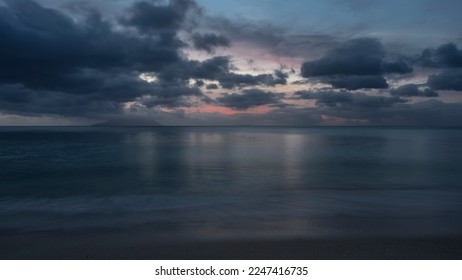 Calm evening seascape in shades of blue. Picturesque clouds in the sky, highlighted in pink. Reflection on the ocean surface. Foam of waves on wet sand. Long exposure. Seychelles. Mahe. Beau Vallon - Shutterstock ID 2247416735