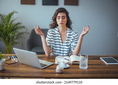 Calm female executive meditating taking break at work for mental balance, mindful businesswoman feeling relief and no stress doing yoga at work ignoring avoiding stressful job and paperwork in office