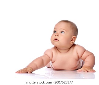 Calm And Focused Infant Child Baby Girl Kid In Diaper Is Lying On Her Tummy, Holding Arm Outstretched, Slapping On Floor And Looking At Upper Corner Isolated On A White Background