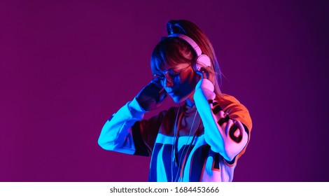 Calm girl wear stylish glasses headphones listen music at purple background.