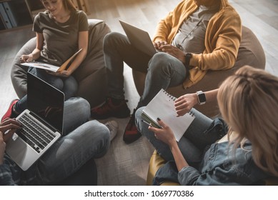 Calm guys and girls taking seats on beanbags and doing their work. Men using notebooks. Woman checking time on smartwatch - Shutterstock ID 1069770386