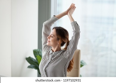 Calm happy businesswoman relaxes in workplace during a break. Smiling woman stretching on work chair, enjoys at work. Relaxation after work is finished. Break, pause. - Shutterstock ID 1197102931