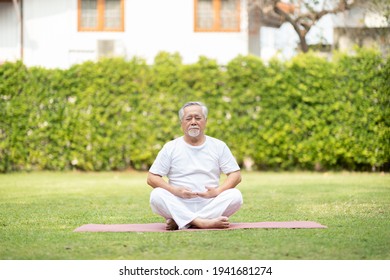 Calm of Healthy Asian Elderly man with white hairs doing yoga lotus pose for meditation on green grass at park,Wellness Senior Recreation with yoga concept