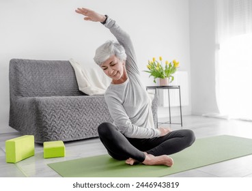 Calm Home Exercises In A Bright Room, A 70-Year-Old Woman Practices Yoga - Powered by Shutterstock