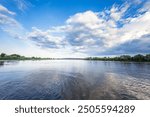 A calm lake with a cloudy sky in the background. The water is still and the sky is overcast