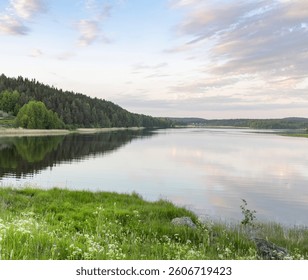 A calm lake with a few trees in the background. The sky is cloudy and the sun is setting - Powered by Shutterstock - Get 15% off with code: PIKWIZARD15