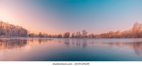 Calm lake water reflections forest trees panoramic sunrise sky. Beautiful silence morning dawn in early spring late winter. Soft bright pink purple colored sky panorama. Beautiful nature landscape - Powered by Shutterstock