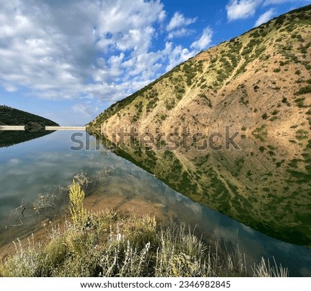 Calm lake water reflects the silhouette of low-vegetated mountains. Stok fotoğraf © 
