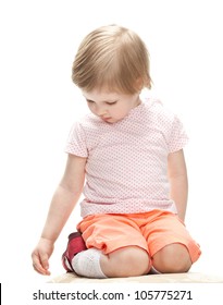 Calm Little Child Sitting And Looking Down, Studio Shot On White Background