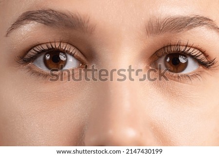 Calm look. Close-up cropped image of beautiful female brown eyes showing different emotions. Youth culture. Natural beauty. Concept of human emotions, facial expression, beauty. Copy space for ad