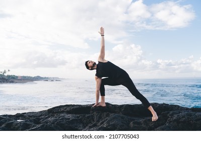 Calm Male In Sportive Wear Standing In Yoga Pose And Meditate During Morning Mindfulness Concentration At Coastline Seashore, Caucasian Man Enjoying Hatha Practice For Enlightenment Harmony