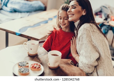 Calm mama hugging her daughter and sitting in sweet cafe. They closing eyes enjoy sweet moment Arkivfotografi