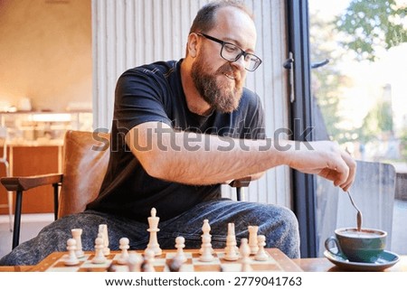 Calm man preparing coffee after game. Serene individual softly mixing coffee in warm room setting. Whitehaired man peacefully stirring coffee next to chess pieces with gentle smile