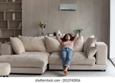 Calm millennial Latino woman lying relaxing on couch in living room breathe fresh ventilated condition air. Happy young Hispanic female renter rest on sofa at home relieve negative emotions. - Shutterstock ID 2013742856