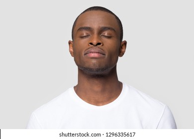 Calm Mindful African American Man Enjoy Taking Deep Breath Of Fresh Air Isolated On White Studio Background, Happy Black Guy With Serene Face Eyes Closed Meditating Feeling Harmony And No Stress Free