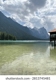 Calm mountain lake reflecting dramatic peaks under cloudy sky in a pristine alpine landscape.