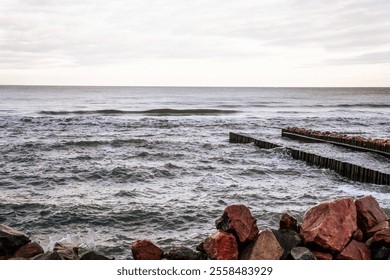 Calm Ocean Waves Gently Lap Against a Rocky Jetty at Dawn Near a Serene Coastline. - Powered by Shutterstock