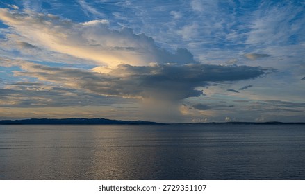 Calm open sea with dramatic clouds and distant shoreline