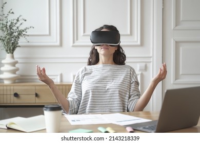 Calm peaceful woman employee meditating in glasses of virtual reality, sitting in zen pose at workplace with laptop computer while working in office, mindful female practicing yoga in VR headset - Powered by Shutterstock