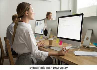 Calm peaceful young businesswoman meditating at office desk with eyes closed, company employee manager practicing yoga at workplace for mental emotional balance, no stress at work relief, side view