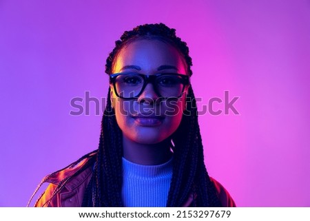 Calm. Portrait of female fashion model in cotton shirt isolated on purple background in neon light. Concept of beauty, art, fashion, youth, sales and ads. Pretty woman looking at camera