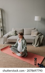 Calm Pregnant Woman Deep Breathing Doing Yoga In Lotus Pose Comfortable At Home.