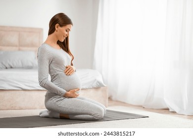 A calm pregnant woman in a peaceful state practicing prenatal yoga in her bedroom - Powered by Shutterstock