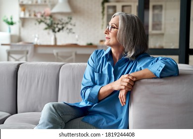 Calm relaxed mature older woman relaxing sitting on couch at home. Peaceful middle aged grey-haired lady resting on sofa in modern living room enjoying lounge and no stress, looking away, thinking. - Powered by Shutterstock