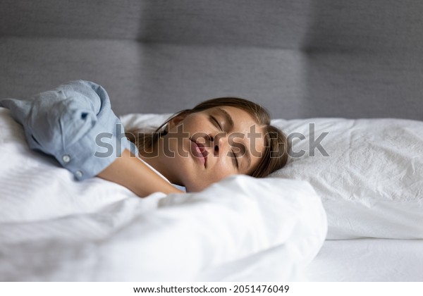 Calm\
relaxed teen girl sleeping in white linen bedclothes of hotel room\
bed, enjoying relaxation, recreation, peaceful bedtime. Serene\
young woman with head rested on pillow candid\
shot
