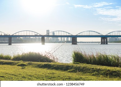 A Calm River And An Arch Bridge And Two Fishing Rods And Green Grass And Blue Sky At Hangang Park, Seoul, South Korea