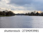 Calm River Landscape Under Dramatic Cloudy Sky with Winter Trees and Navigation Buoys