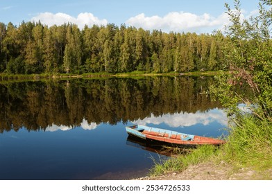 Calm river with trees reflected in the water. Old wooden boat on the river bank. Shuya River in Karelia, Russia
 - Powered by Shutterstock