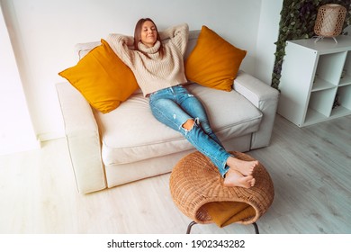 Calm satisfied woman relaxing or sleeping on the sofa in living room. Carefree lady resting at home, enjoying stress free weekend. Day off work. Home lifestyle, home comfort concept. 