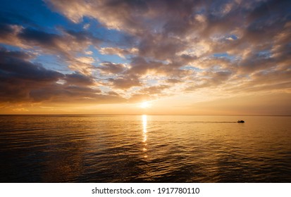 Calm Sea With Sunset Sky And Sun Through The Clouds Over. Meditation Ocean And Sky Background. Tranquil Seascape. Horizon Over The Water. A Little Boat Sails On A Quiet Sea