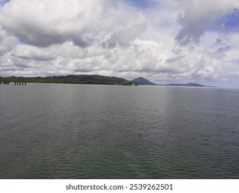 Calm sea view with cloudy skies and distant mountains under a soft light - Powered by Shutterstock